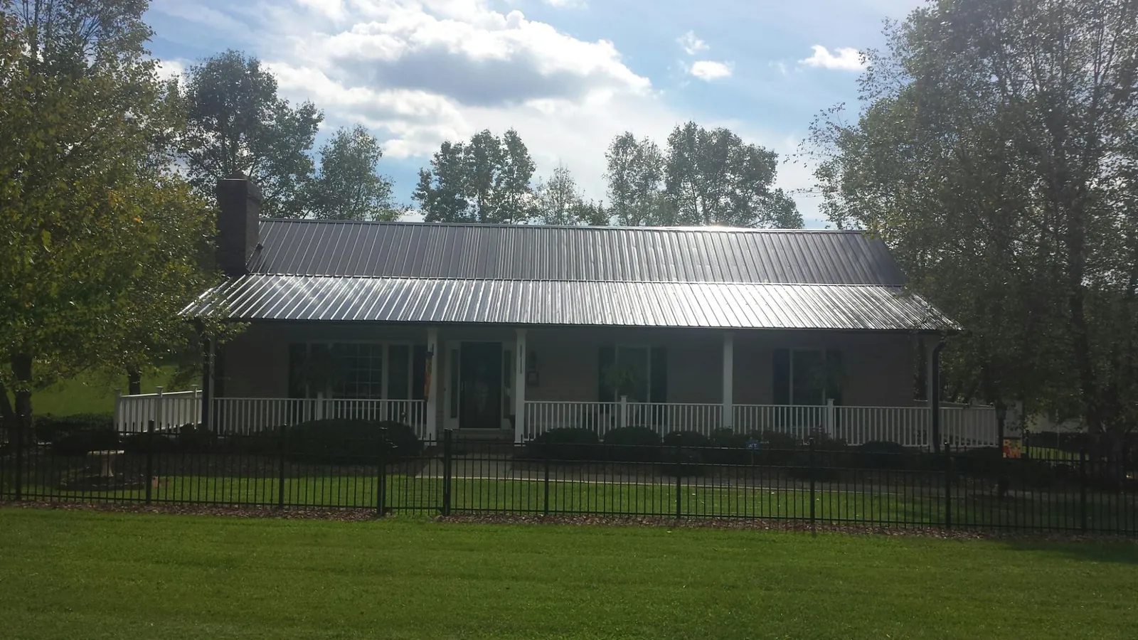 Gray metal roof on a brick ranch with a full width front porch — Gutter Guard Installation work by our crew in Jasper